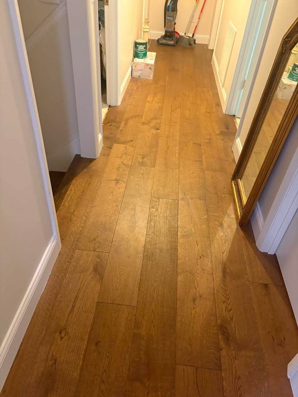 Warm hardwood hallway flooring installation with clean white trim